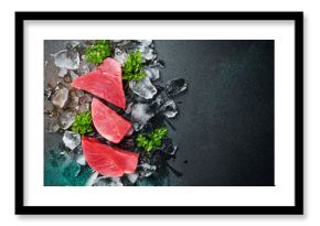 Fresh raw tuna fillet on ice cut into steak on a stone background with seasonings and herbs