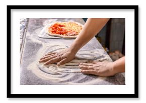Hands preparing a pizza or making a homemade pepperoni pizza. Cook hand makes a pizza, puts the sausage on top. Hand sprinkling cheese on pizza dough with tomato sauce