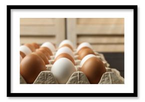 Many raw chicken eggs in carton on table indoors, closeup
