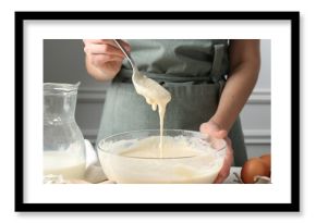 Woman making batter (liquid dough) at white table indoors, closeup