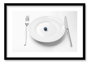 One blueberry on plate and cutlery on white table, closeup