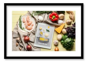 Tablet computer with tasty ingredients on yellow wooden background