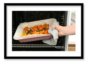 Woman taking baking tray with tasty baked pumpkin, eggplant, bell pepper and zucchini out of oven, closeup
