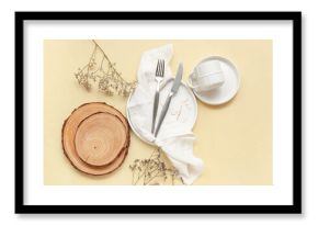 Table setting with cutlery, dishes and wooden boards on beige background