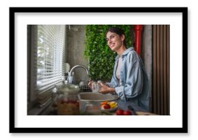 Woman washing dishes at kitchen sink, doing housework