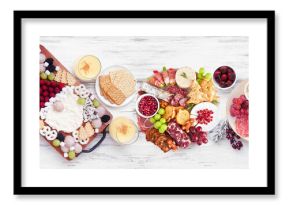 Christmas holiday charcuterie table scene on a white wood banner background. Above view. Assorted cheese, fruit and meat appetizers.