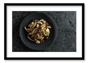 Fried shimeji mushrooms with thyme and garlic on a black plate.