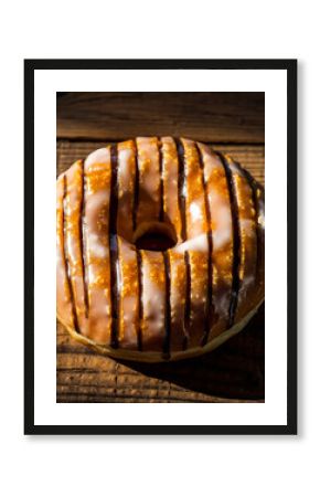 Overhead View of Donut with Dark Caramel Glaze and White Icing Drizzle on Rustic Wood
