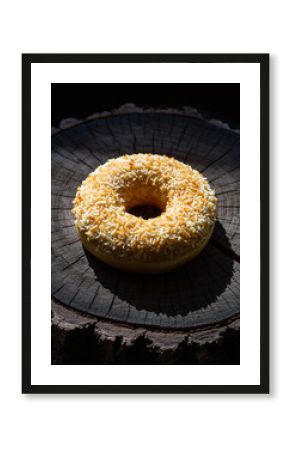Golden Coconut Topped Donut on Rustic Wooden Log Slice with Dramatic Light