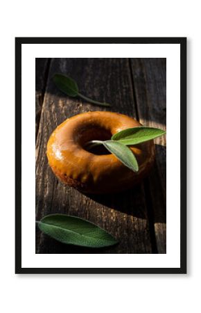 Savory Maple Glazed Donut with Fresh Sage Leaf on Rustic Wood
