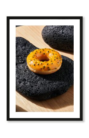 Vibrant Passion Fruit Glazed Donut on Black Lava Rock and Wooden Slab