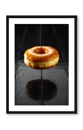 Caramel Glazed Donut Levitating Over Reflective Dark Wooden Table Surface