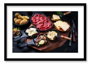 Traditional authentic swiss raclette with beef meat, boiled potatos, green beans and mushrooms served as close-up on a wooden design board