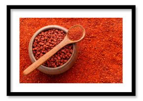 Crushed annatto seeds in the spoon and in the bowl - Bixa Orellana