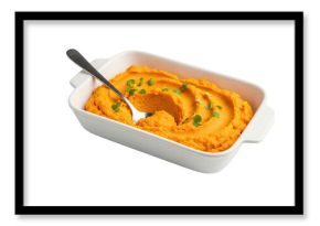 Creamy orange vegetable puree, possibly from carrots or sweet potatoes, served in a white ceramic baking dish with a spoon and garnished with fresh microgreens, isolated on black