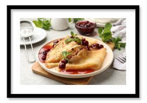 Tasty crepes with cherries, jam and mint served on light table, closeup