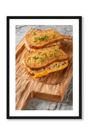 Breakfast Tuna Melt sandwich made of rye bread, canned tuna and melted cheese close-up on a wooden board on the table. Vertical
