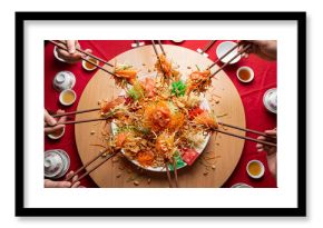 Multiple hands tossing salmon yusheng salad with chopsticks on a round table, festive shared meal for lunar new year celebration and family gathering tradition in Asian cuisine