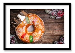 Roscon de reyes with cream and christmas ornaments on a wooden background, top view. Roscon is a traditional Spanish Christmas pastry cake with decoration. Kings day concept spanish three kings cake.