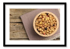 Tasty granola with dried fruits in bowl on wooden table, top view. Space for text