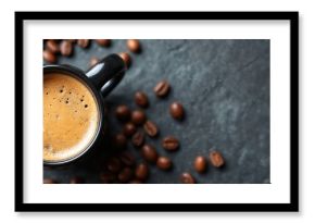 Black mug filled with fresh espresso and rich foam sits on dark stone surface surrounded by roasted coffee beans. A warm morning beverage provides energy and aroma.