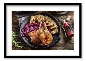 Portion of roast duck leg red cabbage homemade dumplings on plate and red wine on the background