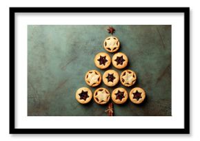 Christmas and New Year food Background with fir tree made from traditional christmas Mince pies, anise stars and cinnamon stickes on a green table surface.