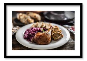 Portion of roast duck leg red cabbage homemade dumplings on plate and red wine on the background