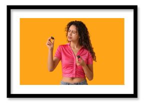 Beautiful young African-American woman with sweet chocolate candies on yellow background