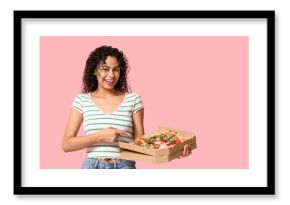 Beautiful young happy African-American woman pointing at delicious pizza on pink background