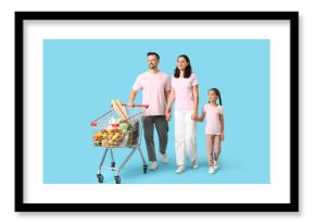 Happy family with full shopping cart holding hands on blue background