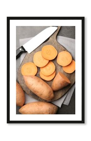 Fresh raw sweet potatoes and knife on gray table, top view