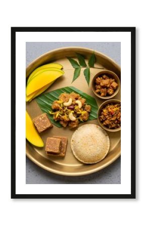 Traditional Indian thali with idli, banana, sweets, and curries on brass plate. Festive South Indian meal for Pongal, Onam, Vishu. Vegetarian cuisine concept.