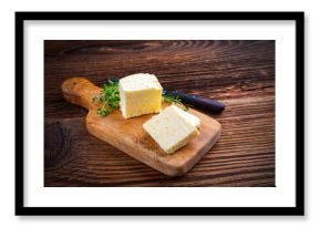 Fresh French sea salt butter garnished with thyme offered as close-up on a rustic wooden chopping board