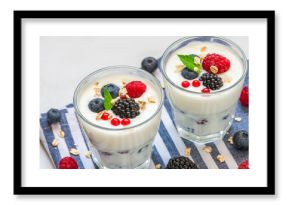 Greek yogurt with fresh berries, oats and mint in glasses on white background. Yoghurt with blueberry, raspberry, blackberry and granola. Healthy breakfast. Diet food