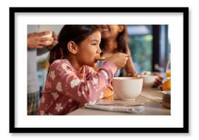 Cute little girl enjoying breakfast with milk and corn flakes