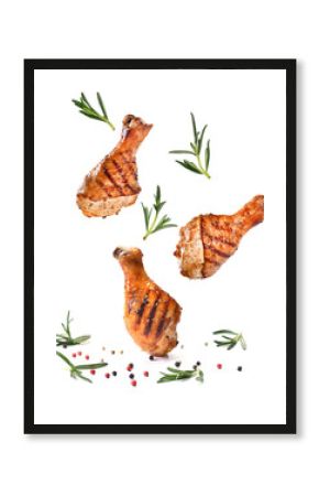 Grilled chicken legs or drumsticks falling down with herbs and colourful peppers isolated on white background. Juicy BBQ chicken drumsticks sprinkled with herbs and seasoning on white background..