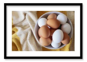 Brown and white eggs in a white bowl overhead photo