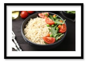 Delicious brown rice with vegetables on black wooden table, closeup
