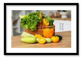 Wicker basket with different fresh vegetables on wooden kitchen counter