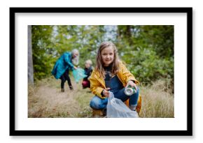 Small girl with mother and grandmother picking up waste outoors in forest.