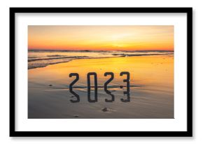 Bonne année 2023 : concept de nouvelle année 2023 avec un lever de soleil sur la plage et les chiffres 2023 en reflet dans la mer.