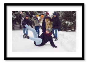 Overjoyed diverse friends in outwear have fun playing snowballs together on winter holidays in forest. Smiling young people laugh relax on leisure weekend in snowy park. Outdoor activity.