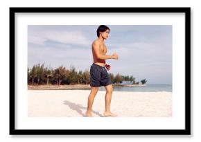 Smiling Asian Man Enjoying Beach Vacation: Torso of a Muscular Guy on Sandy Tropical Island, with Palm Trees, Blue Sky, and Crystal Clear Ocean Water.