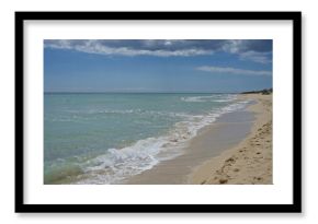 Pristine pescoluse beach in salento, puglia, italy with serene waves gently lap the sandy shore under a partly cloudy sky.