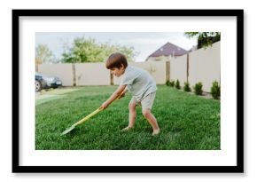 Young boy gardening with a vibrant yellow shovel, enjoying outdoor activity, sunny day, and connecting with nature. Playful and energetic scene in a green lawn.