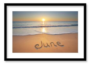 June word written on the sandy sea coast shore.