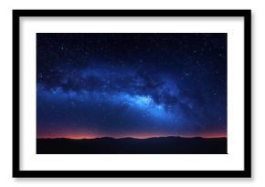 Panoramic night sky with a bright band of stars and the Milky Way over a dark mountain silhouette at dusk
