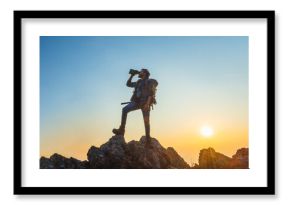 man is standing on a mountain top, looking through a camera lens