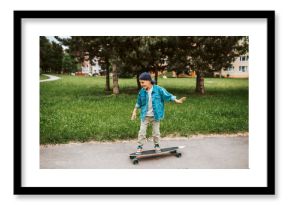 Young boy Learning to ride longboard on street.